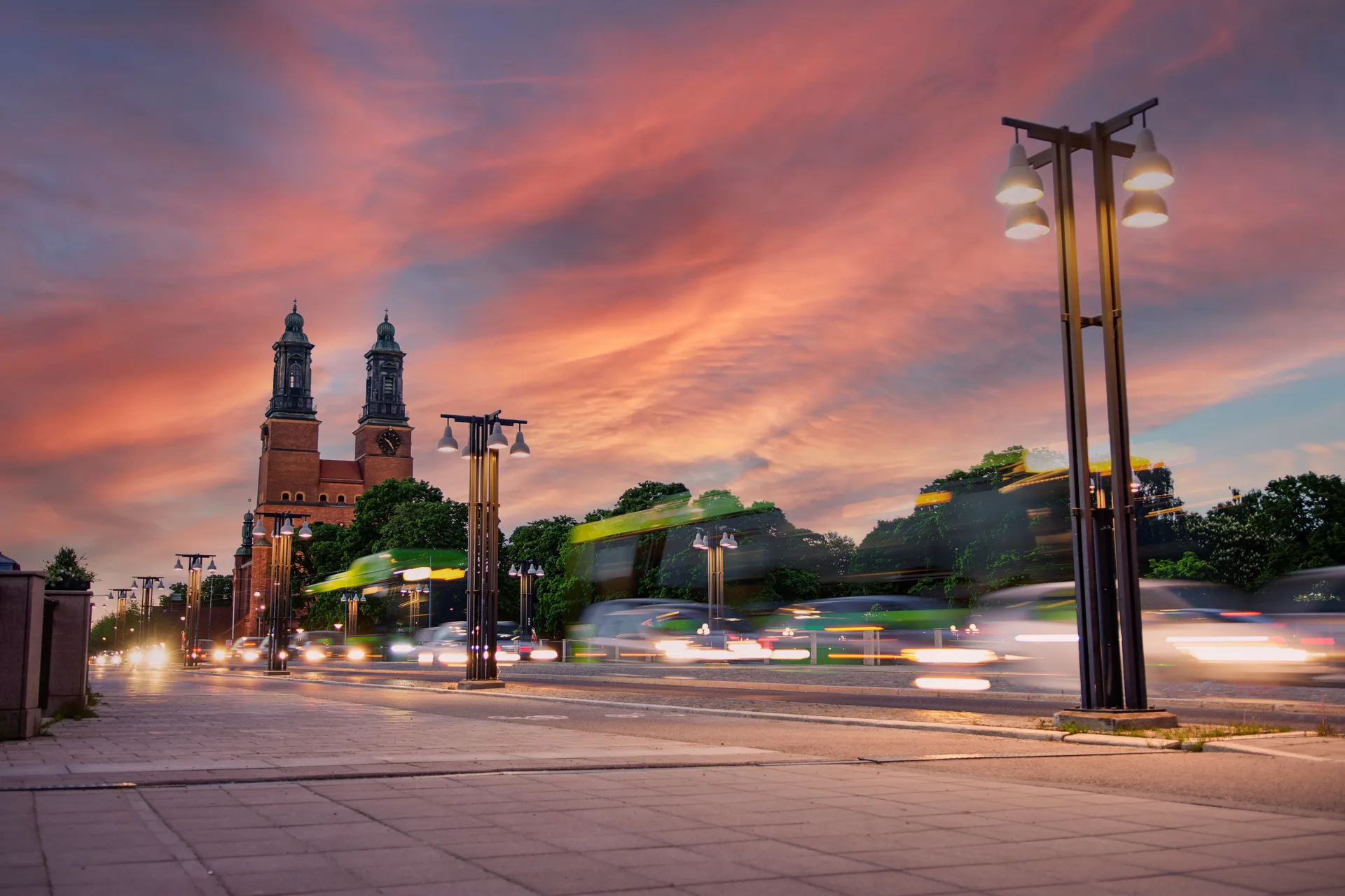 Kvällstrafik i rörelseoskärpa längs en upplyst gata i Eskilstuna under en rosafärgad himmel